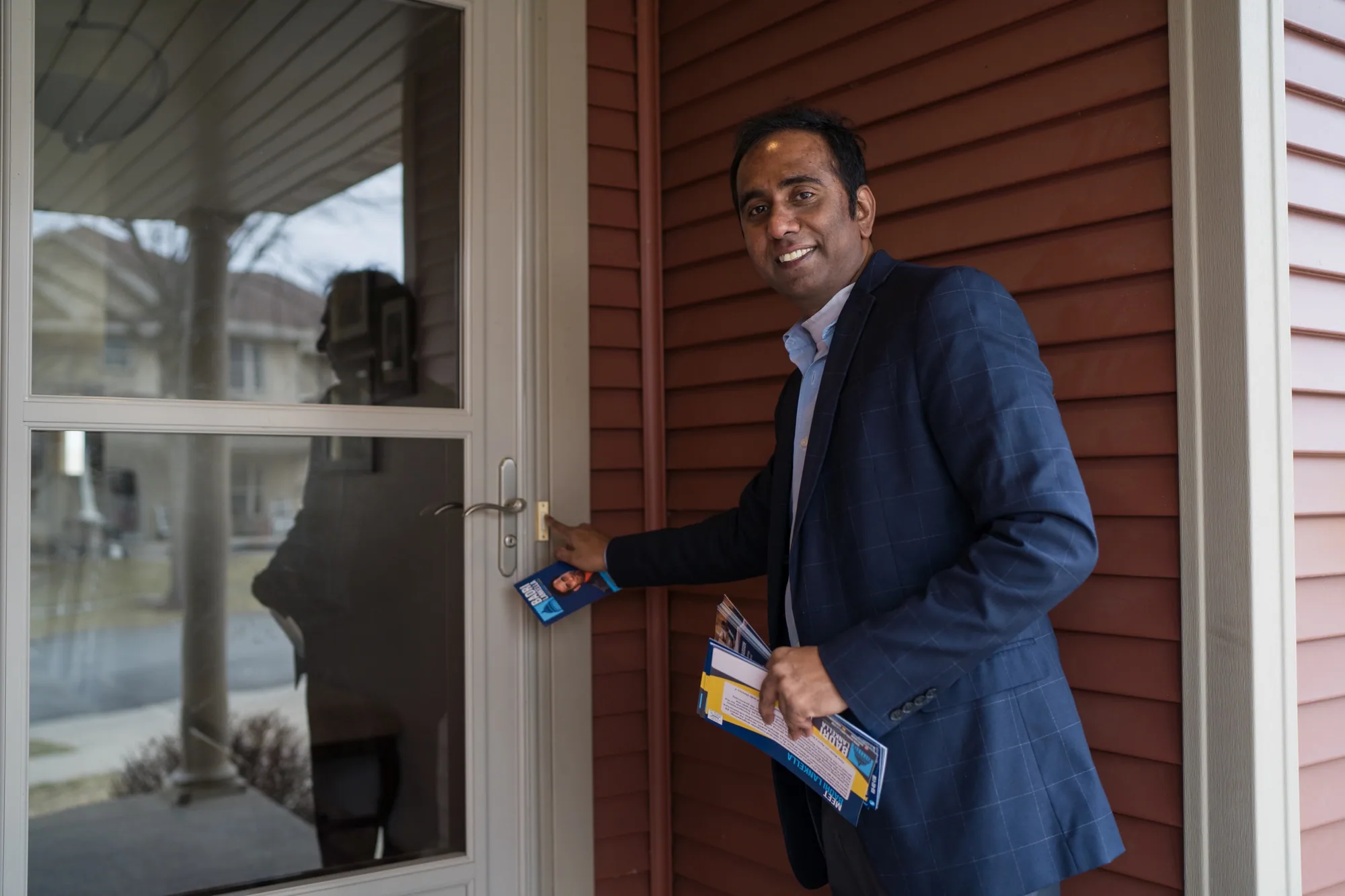 A campaign canvasser at a front door holding outreach literature